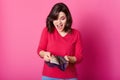 Girl with purple wallet full of money in hands looks astonished. Surprised woman wears shirt, holds opened purse, being glad to Royalty Free Stock Photo