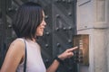 Girl that is pushing a button of the house intercom outdoors in front of a huge antique door. Royalty Free Stock Photo