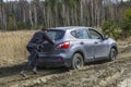 Girl pushing stuck car at swamp dirt road