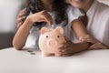 Girl put coin into piggybank, caring of budget with mother Royalty Free Stock Photo