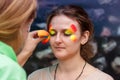 Girl put a picture on her face. Make-up of paints on a body for a carnival. An adult woman is painted for a birthday party.