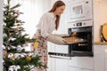 The girl puts a baking tray with Christmas cookies in the oven Royalty Free Stock Photo