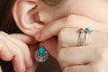 The girl puts on a earring with a turquoise stone on her ear