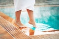 A girl puts her foot in a pool with hot thermal water, a wellness vacation at hot springs