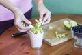 The girl puts the pieces of green apples in a glass of yogurt Royalty Free Stock Photo