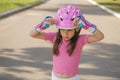 The girl puts a pink sports protective helmet on her head for skateboarding Royalty Free Stock Photo