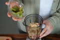 The girl puts the sliced kiwi in a blender