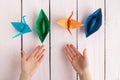 A girl puts together an origami crane and a boat made of colored paper. On a wooden background Royalty Free Stock Photo