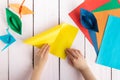 A girl puts together an origami crane and a boat made of colored paper. On a wooden background Royalty Free Stock Photo