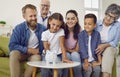 Girl is putting a coin in family white piggy bank while all family is looking at her at home. Royalty Free Stock Photo