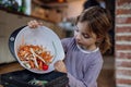 Girl putting kitchen waste, peel and leftover vegetables scraps into kitchen compostable waste. Concept of composting