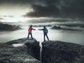 Girl is putting lightning lantern over rocky edge to man hands Royalty Free Stock Photo