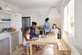 Girl putting plates on table for her family while mum cooks