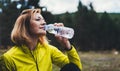 Girl quenches thirst after fitness. Smile person drinking water from plastic bottles relax after exercising sport outdoors, woman Royalty Free Stock Photo