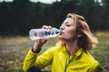 Girl quenches thirst after fitness. Smile person drinking water from plastic bottles relax after exercising sport outdoors, woman