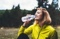 Girl quenches thirst after training fitness. Smile person drinking water from plastic bottles relax after exercising sport outdoor Royalty Free Stock Photo