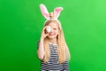 Girl in rabbit bunny ears on head on green studio background. Cheerful crazy smiling happy child. Easter painting eggs