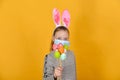 A girl with rabbit ears and a protective mask against coronavirus holds Easter eggs in her hand on a holiday Royalty Free Stock Photo