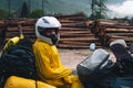 A girl in a raincoat, shoe covers and a helmet is sitting on big adventure motorbike. Vacation and travel. Rain and felling after