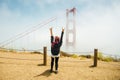 Girl with raised hands relaxing on top of the mountain, enjoying beautiful view. Hiking trip. Golden Gate Bridge, over Pacific