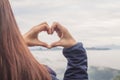 The girl raises her hand to show a meaningful heart-shaped symbol. Tell her that I love you on a blurred background of nature. The