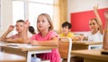 Girl raising hand to answer during lesson at classroom Royalty Free Stock Photo