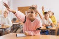 Girl raising hand to answer during lesson Royalty Free Stock Photo