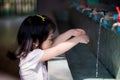 Girl reaching out to wash hands in sink, opening the faucet to let water run through her hand. Royalty Free Stock Photo