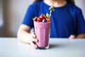 girl reaching over to grab a blueberry smoothie Royalty Free Stock Photo