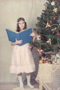 Girl reading book around Christmas tree Royalty Free Stock Photo