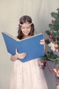 Girl reading book around Christmas tree Royalty Free Stock Photo