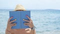 Girl reading a book on the beach wearing straw hat Royalty Free Stock Photo