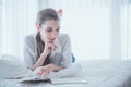 Girl reading a book in bed, lay down on her stomach smiling happy and relaxed on a leisure day at home Royalty Free Stock Photo