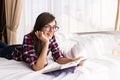 Girl reading a book in bed, lying on her stomach smiling happy and relaxed on a leisure day Royalty Free Stock Photo