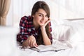 Girl reading a book in bed, lying on her stomach smiling happy and relaxed on a leisure day Royalty Free Stock Photo