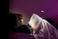 Girl reading a book in bed at night in comfy bedroom wearing pyjamas