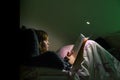 Girl reading a book in bed at night in comfy bedroom wearing pyjamas