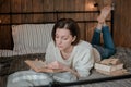 Girl reading a book and drinking coffee in bed feet on the wall. Royalty Free Stock Photo