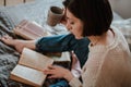 Girl reading a book and drinking coffee in bed feet on the wall. Royalty Free Stock Photo