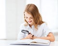 Girl reading book with magnifier at school