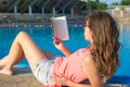 Girl reading a book by the pool. Royalty Free Stock Photo