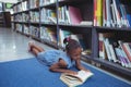 Girl reading book by shelf in library Royalty Free Stock Photo