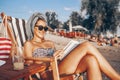 Girl reading a book while sitting on deck chair Royalty Free Stock Photo