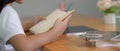 A girl reading book to doing her homework on wooden worktable with mock-up tablet Royalty Free Stock Photo