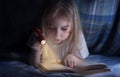 Child reading a book under the covers. Immersion into the magical world Royalty Free Stock Photo