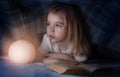 Child reading a book under the covers. Immersion into the magical world Royalty Free Stock Photo