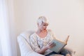 Girl reading a book in a white armchair Royalty Free Stock Photo