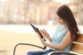 Girl reading an ebook or a tablet in a park
