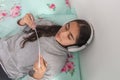 Girl reading on her bed with headphones