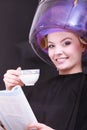 Girl reading magazine drinking coffee. Hairdryer in hair beauty salon Royalty Free Stock Photo